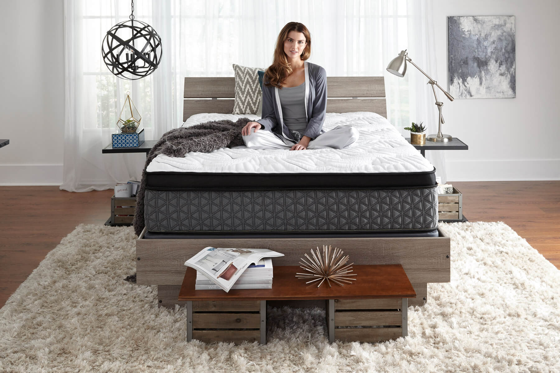 Woman sitting on bed in her pajamas in a stylish bedroom.
